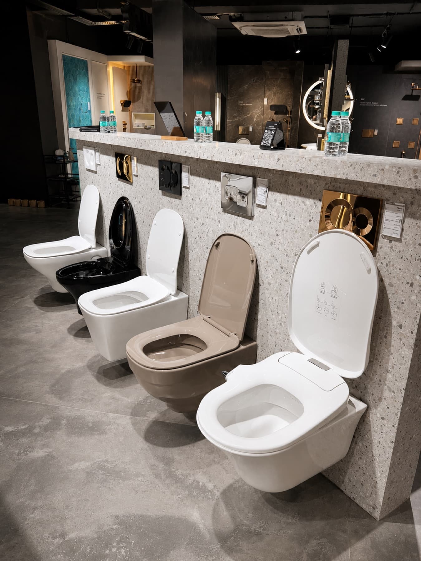 Kohler wall-hung toilets in white, black and truffle with brass and chrome flush plates at Tayo Living, Gurgaon